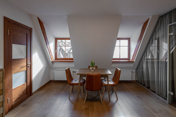 Modern contemporary interior of hall with table and chairs. Sloping ceiling. Private house.