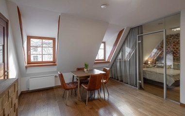 Modern contemporary interior of hall room with table and chairs. Sloping ceiling. Private house.