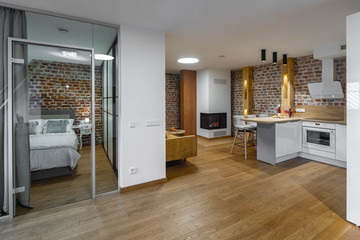 Modern contemporary interior of studio apartment. Private house. Brick wall. Kitchen set. Bedroom.
