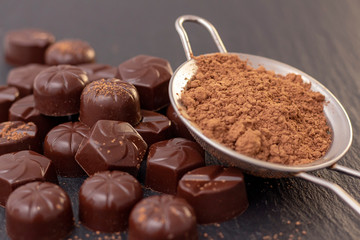 chocolate candies on a black background, cocoa powder. dark photo, mood.