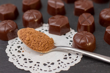 chocolate candies on a black background, cocoa powder. dark photo, mood.