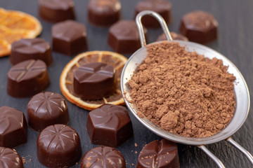chocolate candies on a black background, cocoa powder. dark photo, mood.