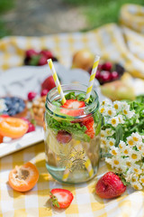 Mason jar glass of lemonade with lemons, strawberry and mint leaves
