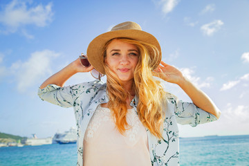 Beautiful blonde in a hat on the beach. Smiling young girl. The beautiful blonde.
