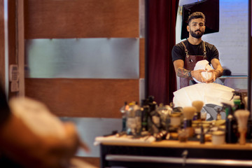 Master cuts hair and beard of men in the barbershop, hairdresser makes hairstyle for a young man