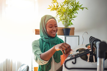 Muslim woman designer as a startup business owner working in tailor shop. Small business owener. Beautiful young African woman working  in workshop. Online shopping makes happy a lot of people