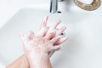 Washing hands with soap under the faucet with water