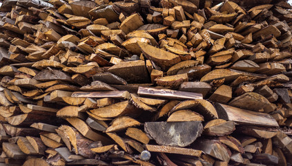 Chopped dry firewood prepared for the winter lying in a heap one on one on the street. Background of logs, birch, pine and oak. Ready to Burn in Fireplace