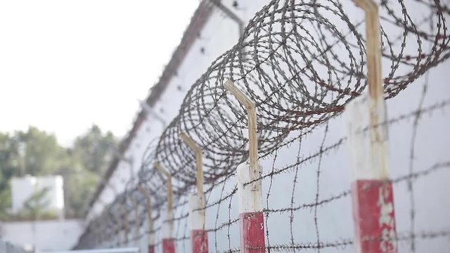 wall of the prison building high fence with barbed wire