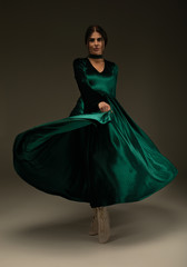 Woman in beauty fashion green gown, beautiful girl dancing in long evening dress.