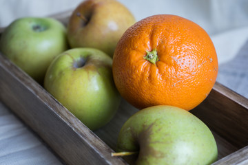 still life with apples and orange in a wooden box on a background of drapery. Staging for drawing art school