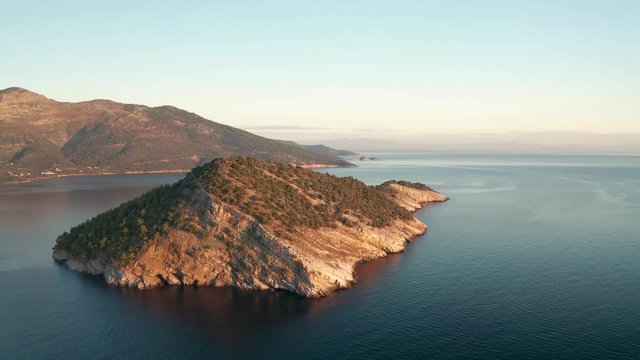 Drone flight around the mountain slopes and rocky coastline of Thasos island and the little island Nisida Kinira, Greece