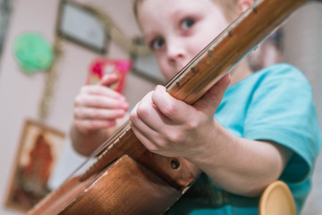 A boy European 5 6 years learn play on old guitar. Work and patience to learn the instrument. Perform tasks at home.