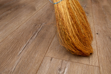 Sweep the floor with a broom made of light gray laminate. Cleaning the apartment with a broom.