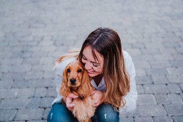 young woman at the street hugging her cute cocker dog. Lifestyle outdoors with pets