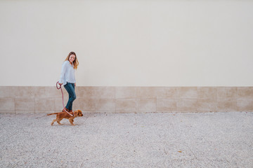 young woman at the street walking with her cute cocker dog. Lifestyle outdoors with pets
