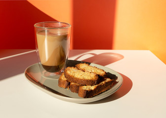 Biscotti almond cookies and a cup of coffee on the table on orange background. Geometric minimalist composition with shadow.