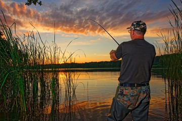 angler catching fish in the lake during sunset