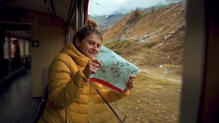 Happy and excited female traveler look out of train window. Young adult on trip of lifetime, student on vacation or interrail european trip. Exciting adventure on swiss bernina train. Wandelust inspo