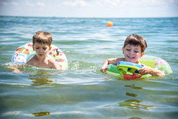 Child in swimming pool floating on toy ring. Kids swim. Colorful rainbow float for young kids. Little boy having fun on family summer vacation in tropical resort. Beach and water toys. Sun protection.