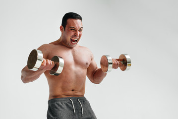 Naked athlete brightly and emotionally performs exercises with dumbbells. Fitness