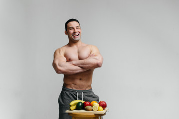 Sexy vegan guy with a naked torso posing in the Studio next to fruit. Diet. Healthy diet