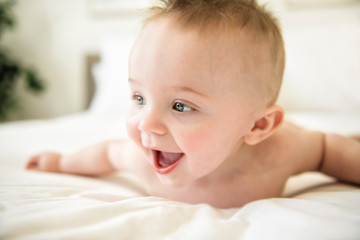 cute baby boy lying on a white bed