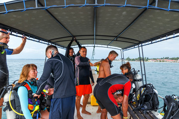 Scuba Divers team with diving equipment is sitting on boat in the Sri lanka sea and smiles