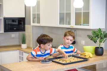 happy family funny kids are preparing the dough, bake cookies in the kitchen. Put berry and blueberry in all biscuits