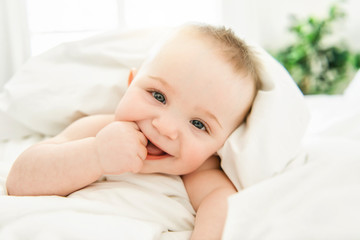 cute baby boy lying on a white bed