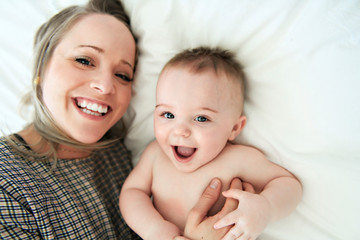 young mother on a bed and holding is baby.