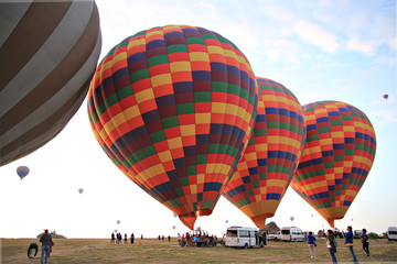 Preparing for take-off hot air balloons with tourists on sunrise.