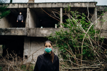 Two people in masks in a abandoned location.Abandoned city ruins. Divided by incurable infectious disease,catastrophe.Isolation.Loved one illness,distance.
