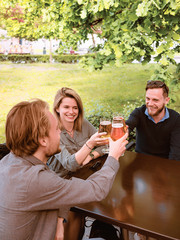 Smiling young friends clinking glasses of beer