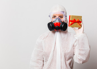 female doctor in protection suit and glasses with mask holds gift box