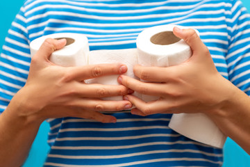 man holds an armful of rolls of toilet paper. the hype around the demand for toilet paper during...
