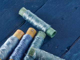Blue and colored silk threads on paper sleeves.Vintage threads lie on a blue background