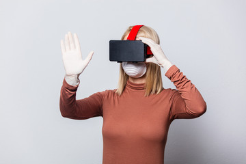 Style blonde woman in face mask with VR glasses on white background