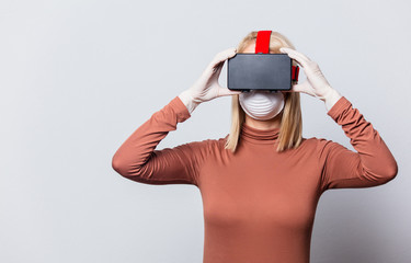 Style blonde woman in face mask with VR glasses on white background