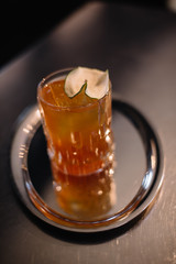 Bartender makes a cocktail based on jin and bergamot tea cordial in a rocks glass and puts a stamp on ice. Smooth image with shallow depth of field.
