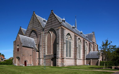 Fototapeta na wymiar Backside of the late gothic hall church with its brick naves in Brouwershaven city in the Netherlands