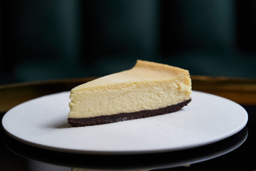 Cup of tea and slice of cheesecake on white plate on table