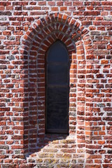 Texture of a simple gothic window arch on the brick facade at Plompe Toren church tower in the sunken village of Koudekerke, Netherlands