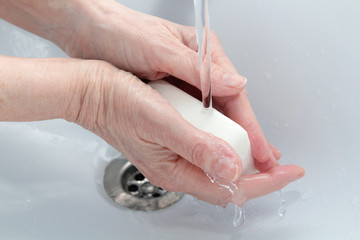 Washing of hands with soap under running water.