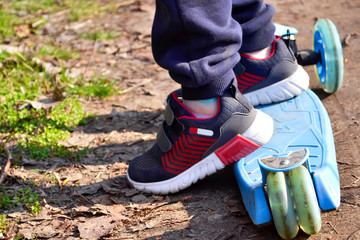 Obraz premium The child rides a scooter. On the scooter are the feet of a boy.