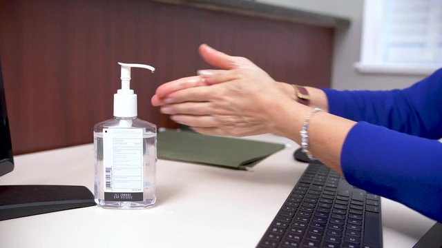 392 Secretary cleaning hands with hands sanitizer at her desk