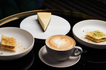 Cappuccino coffee cup and cake on plate on table, close-up.