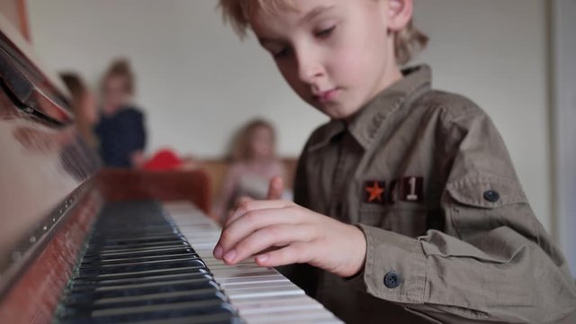 An eight-year-old boy plays the piano at home.