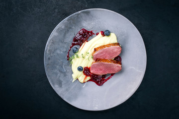 Traditional gourmet duck breast filet with mashed potatoes and cranberry sauce as top view on a modern design plate with copy space - obrazy, fototapety, plakaty