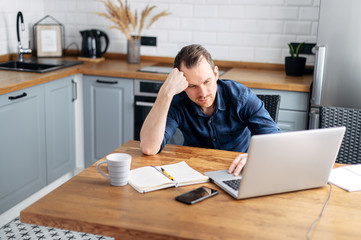 Young man working from home using laptop.